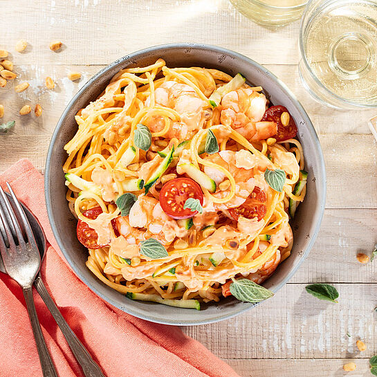 Pasta italienischer Art. Spaghetti mit Garnelen, frischen Zucchini, Cherrytomaten und Pinienkernen. 