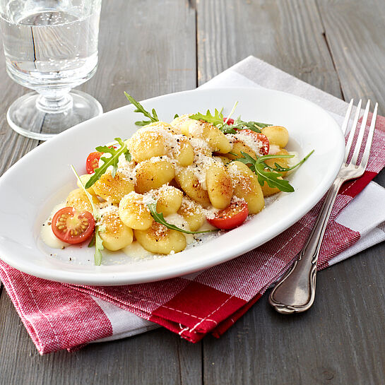 Italienische Gnocchi mit Käse-Sahne-Soße, Grana Padano, Kirschtomaten und Rucola Salat. 