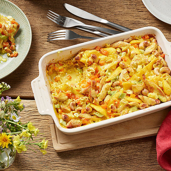 Frisch zubereiteter Mango-Curry-Auflauf mit Hühnchen in einer Auflaufform. Indisch angehaucht mit einer cremigen Soße. 