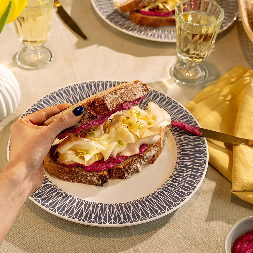 Köstliches Rote-Bete Rezept – Sandwich gefüllt mit cremigem Rote-Bete-Hummus, Fol Epi Käse und frischen Sprossen, serviert auf knusprigem Roggenvollkornbrot.