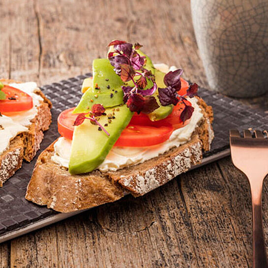 Frische Avocadoscheiben auf knusprigen Brot mit cremigen Brunch Natur Frischkäse