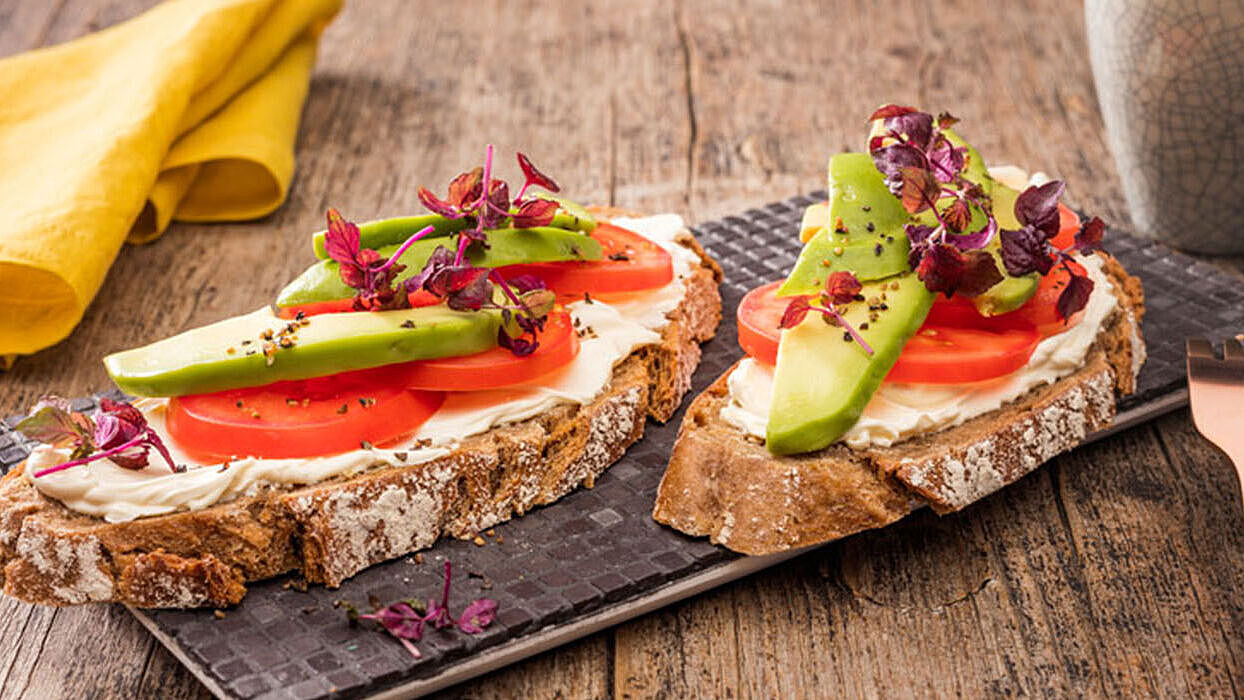 Frische Avocadoscheiben auf knusprigen Brot mit cremigen Brunch Natur Frischkäse