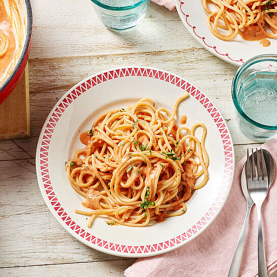 Schüssel mit Pasta und italienischer Tomaten Käse Soße. Leckerer MILKANA Schmelzkäse macht die Soße cremig zart