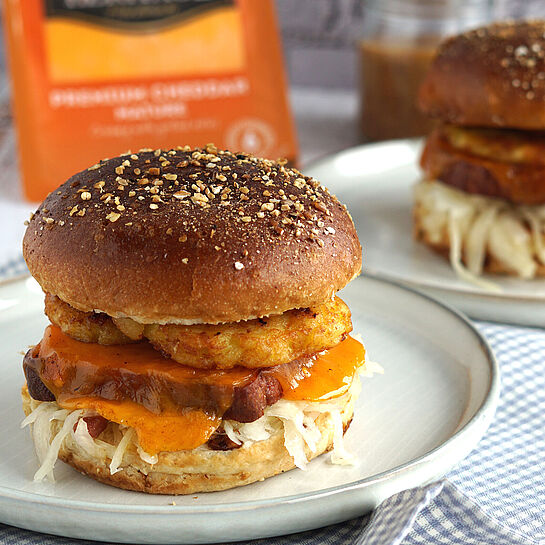 Burger Rezept – Herzhafte Leberkäse-Burger mit Kartoffelrösti, Cheddar, Krautsalat und süßem Senf auf gerösteten Laugenbrötchen.