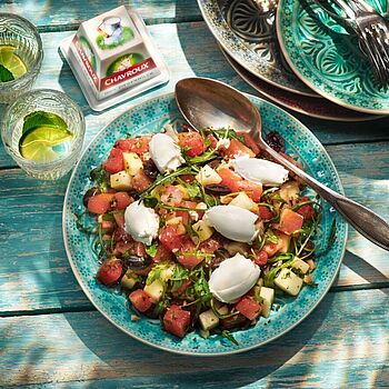 Erfrischender Wassermelonensalat mit Chavroux, knackigem Rucola, Walnüssen und frischer Minze, an einem sonnigen Sommertag auf der Terrasse serviert.