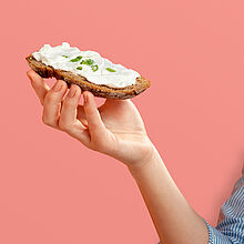 Ziegenfrischkäse auf Vollkornbrot, garniert mit Schnittlauch, eine appetitliche und gesunde Mahlzeit.