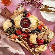 Käseplatte mit Fol Epi Käse, frischen Beeren, Oliven und hausgemachtem Rhabarber-Chutney, angerichtet auf einem rustikalem  Holzbrett.