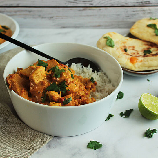 Cremiges Chicken Tikka Masala mit Hähnchenstücken in einer gewürzreichen Tomatensauce, verfeinert mit frischem Koriander.