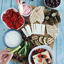 Das Griechische Food Board bietet eine bunte Vielfalt aus Oliven, Feta, gefüllten Weinblättern und Tsatsiki, perfekt angerichtet für gesellige Abende.