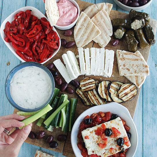 Das Griechische Food Board bietet eine bunte Vielfalt aus Oliven, Feta, gefüllten Weinblättern und Tsatsiki, perfekt angerichtet für gesellige Abende