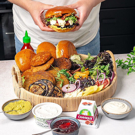 Ein leckeres und exotisches Burger Board mit Lachs, Kichererbsen-Patties, frischem Gemüse, verschiedenen Käsesorten und würzigen Saucen.