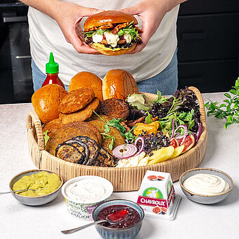 Ein leckeres und exotisches Burger Board mit Lachs, Kichererbsen-Patties, frischem Gemüse, verschiedenen Käsesorten und würzigen Saucen.