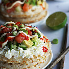 Sushi-Waffeln: Knusprige Waffeln mit Sushireis, frischem Lachs, Avocado, Gurke und Frischkäse, verfeinert mit Sriracha und schwarzem Sesam.