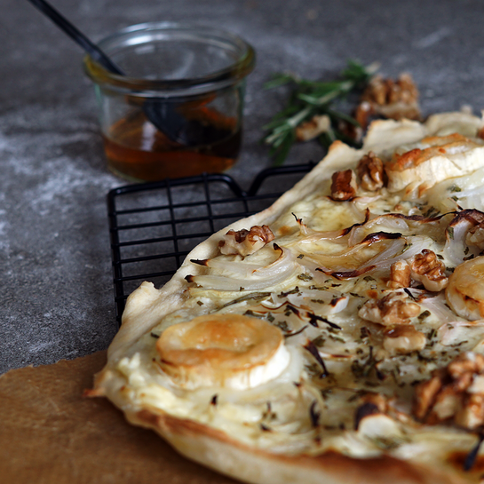 Knuspriger Flammkuchen belegt mit Chavroux-Ziegenkäse, Walnüssen, Zwiebeln und Honig