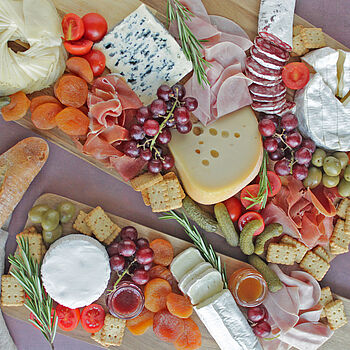 Eine köstliche französische Charcuterie-Platte mit verschiedenen Käsesorten, frischen Früchten und herzhaften Beilagen, perfekt für gesellige Abende.