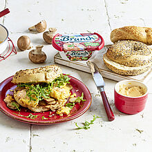 Tolle Frühstückkomposition mit Bagels, Brunch Aufschnitt, Pilzen, Rucola und Rührei. Als Mittelpunkt ein belegtes Frühstückbagel