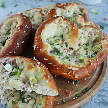 Flammkuchen-Brezel mit knusprigem Laugengebäck, cremiger Käse-Schinken-Füllung und frischen Frühlingszwiebeln - ein herzhafter Snack.