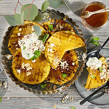 Gegrillte Honig-Ananas-Scheiben mit cremiger Brunch-Dip-Creme, knusprigen Kokoschips und gesalzenen Erdnüssen.