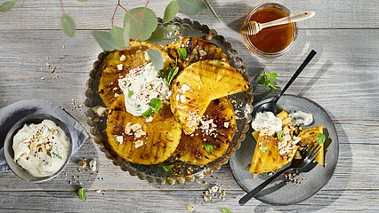 Gegrillte Honig-Ananas-Scheiben mit cremiger Brunch-Dip-Creme, knusprigen Kokoschips und gesalzenen Erdnüssen.