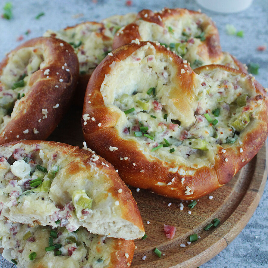 Flammkuchen-Brezel mit knusprigem Laugengebäck, cremiger Käse-Schinken-Füllung und frischen Frühlingszwiebeln - ein herzhafter Snack.