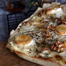 Knuspriger Flammkuchen belegt mit Chavroux-Ziegenkäse, Walnüssen, Zwiebeln und Honig