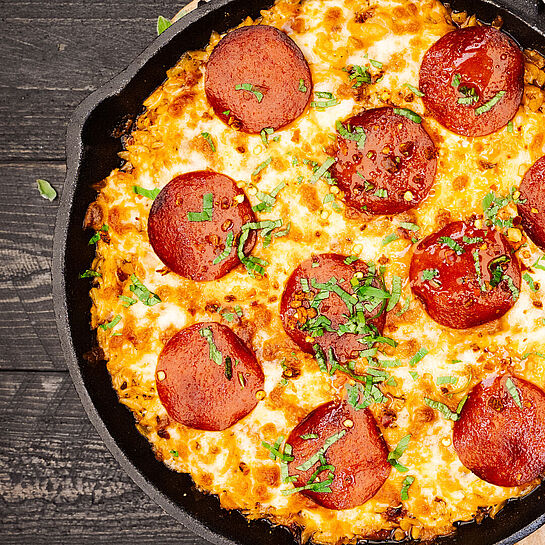 Eine verlockende Pizza Orzo Pasta mit geschmolzenem Mozzarella, knusprigem Speck und würziger Peperoni-Salami.