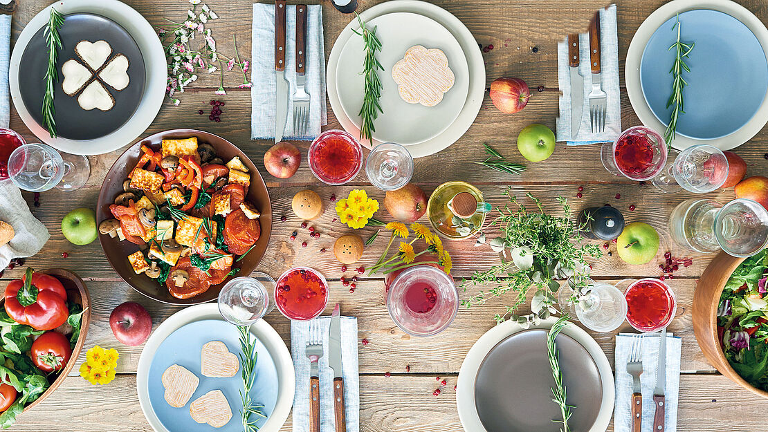 Bunt dekorierter Tisch zum Frühlingsanfang mit Blumen, Obst und Gemüse