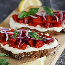 Knusprige Sauerteig-Stulle, belegt mit Zitronenfrischkäse, gegrillter Paprika und Zwiebelstreifen.