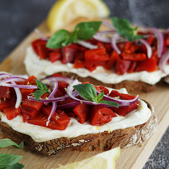 Knusprige Sauerteig-Stulle, belegt mit Zitronenfrischkäse, gegrillter Paprika und Zwiebelstreifen.