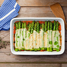 Große Auflaufform mit frischem grünen Spargel aus dem Backofen. Mit Käse überbacken in Tomatensoße. 